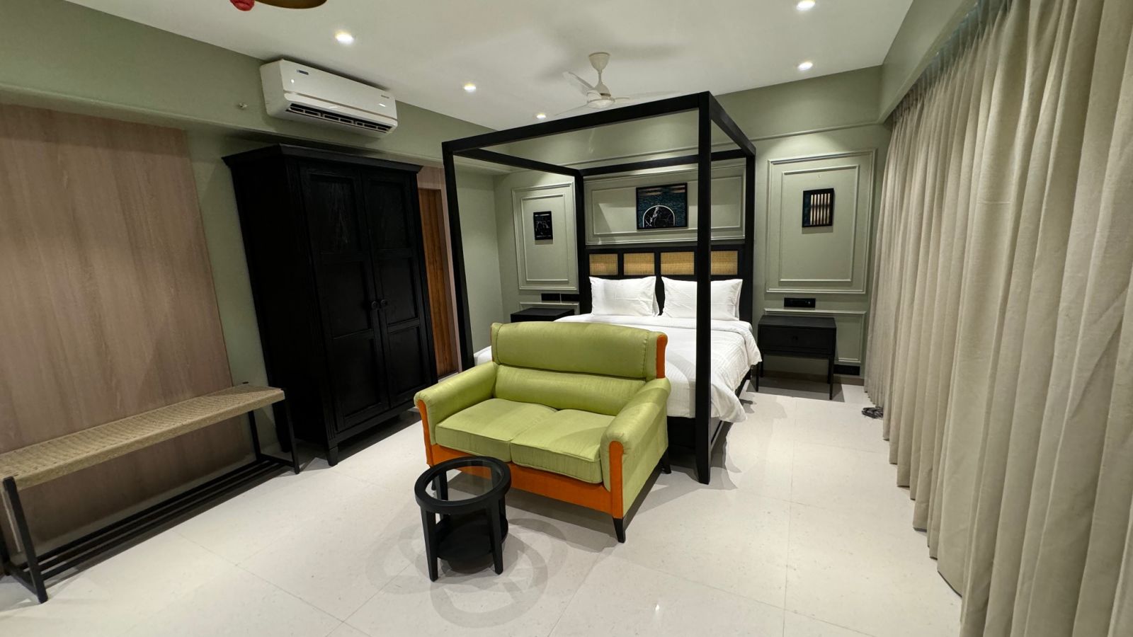 side view of a king bed with a sofa in front of it inside luxury room - Hotel Mumbai House, Malad