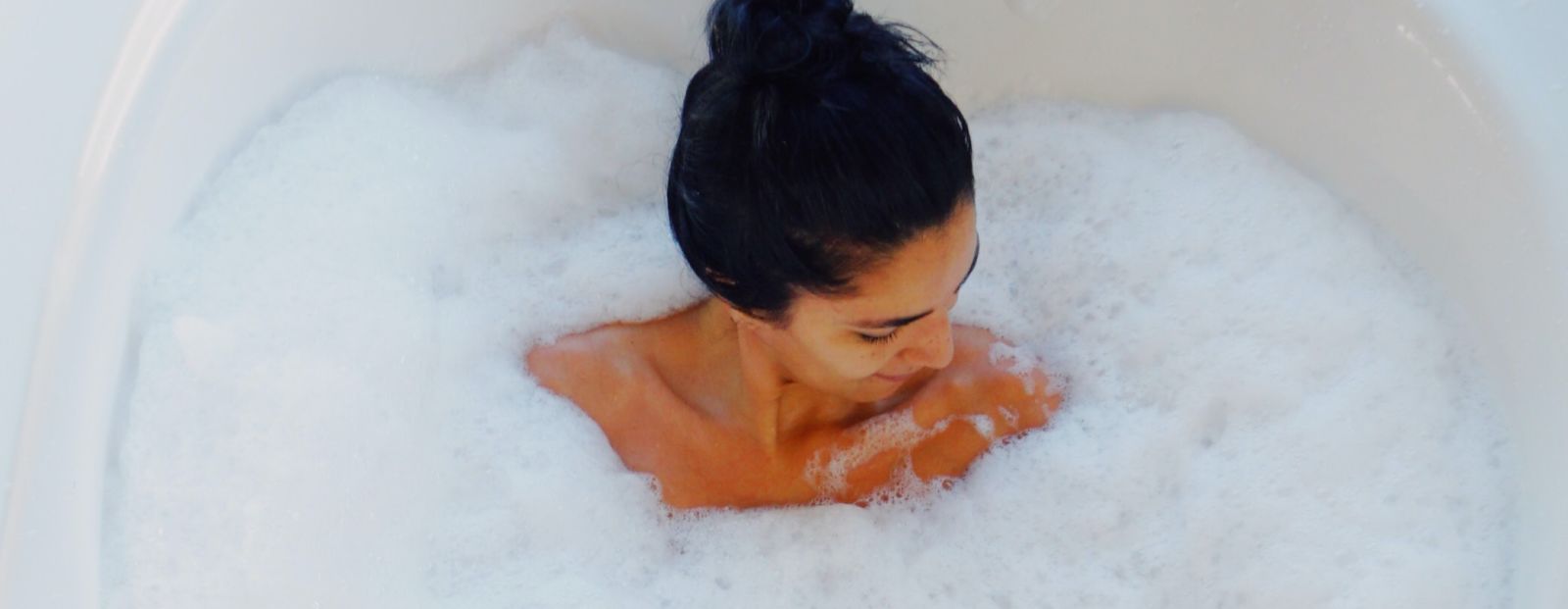 A woman surrounded by froth in a bath tub - Gamyam Retreat