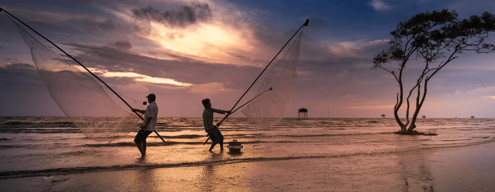 Two man casting out their net to  fish by the seashore