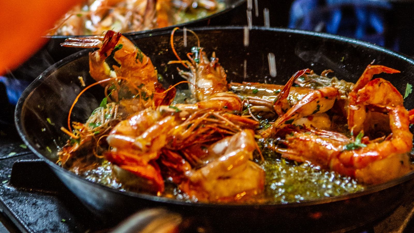 Shrimp being cooked on a stove by a person