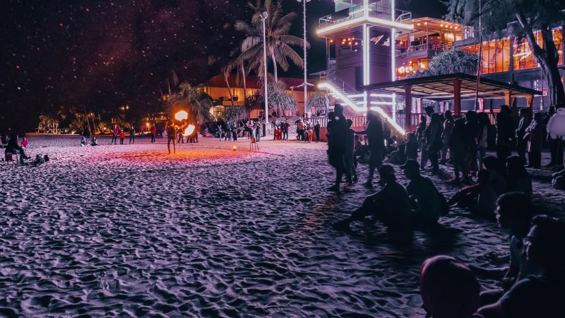 People enjoy a beach party with a brightly lit shack at the distance - Havelock Island at Night