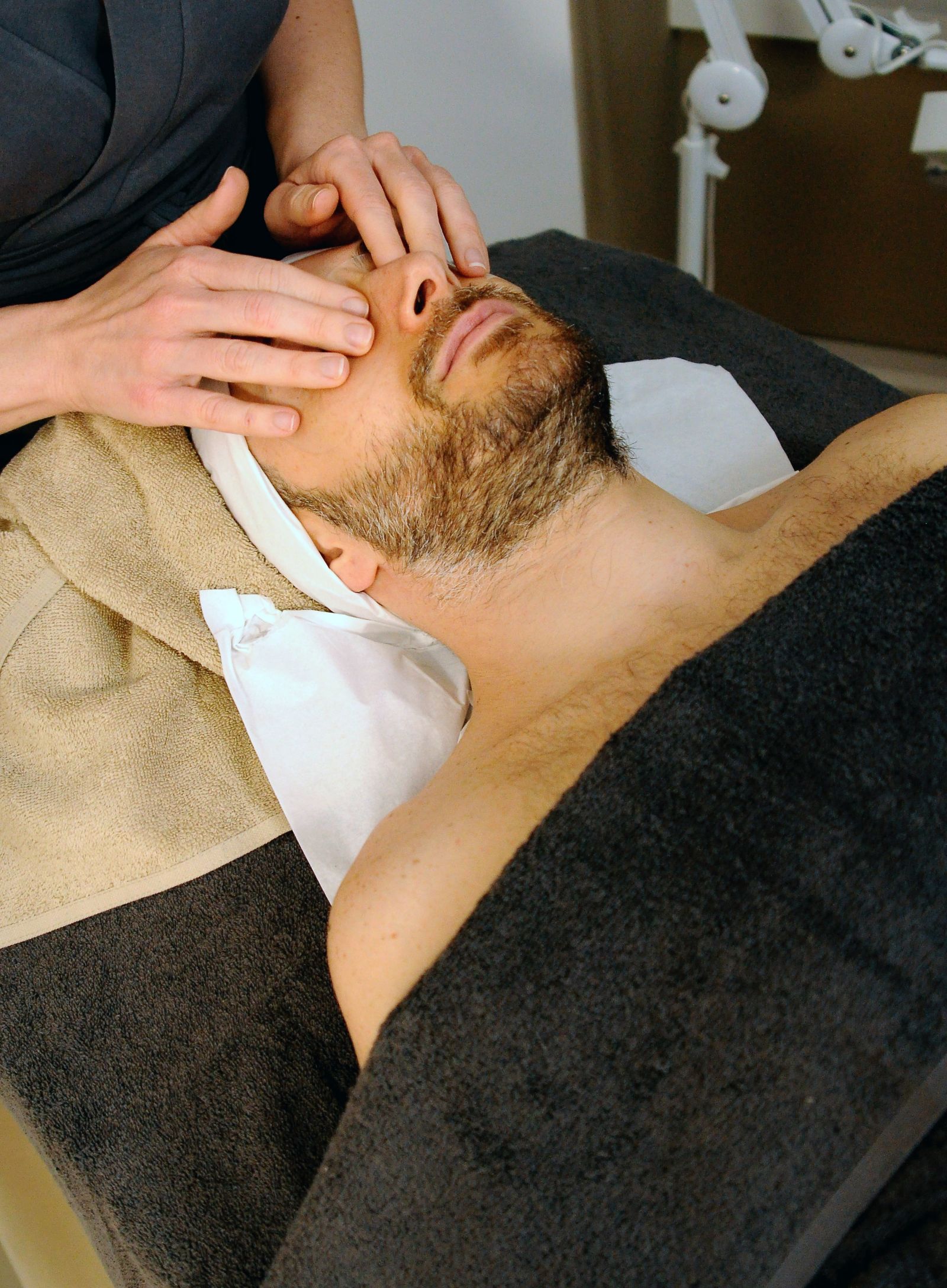 A man lying on a spa bed to get a face massage