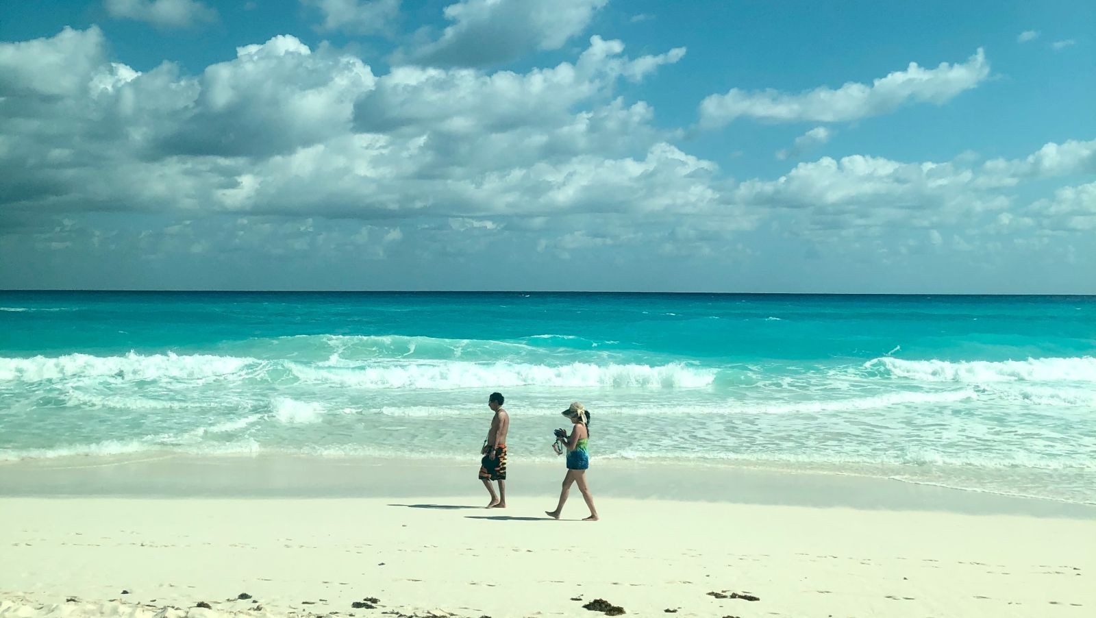 a couple on a sandy beach with the sea and cloudy sky in the background