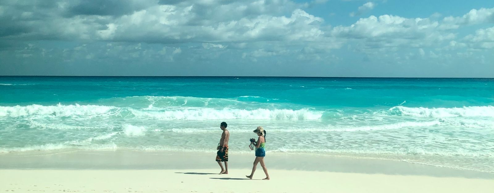 a couple on a sandy beach with the sea and cloudy sky in the background