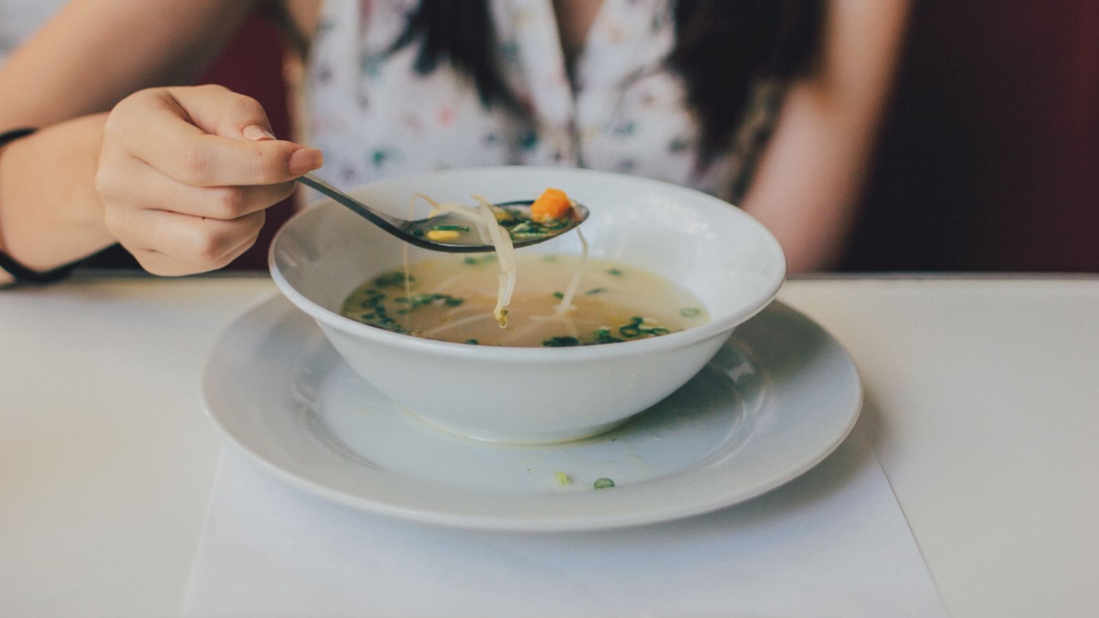 a woman having a shrimp soup served in a bowl