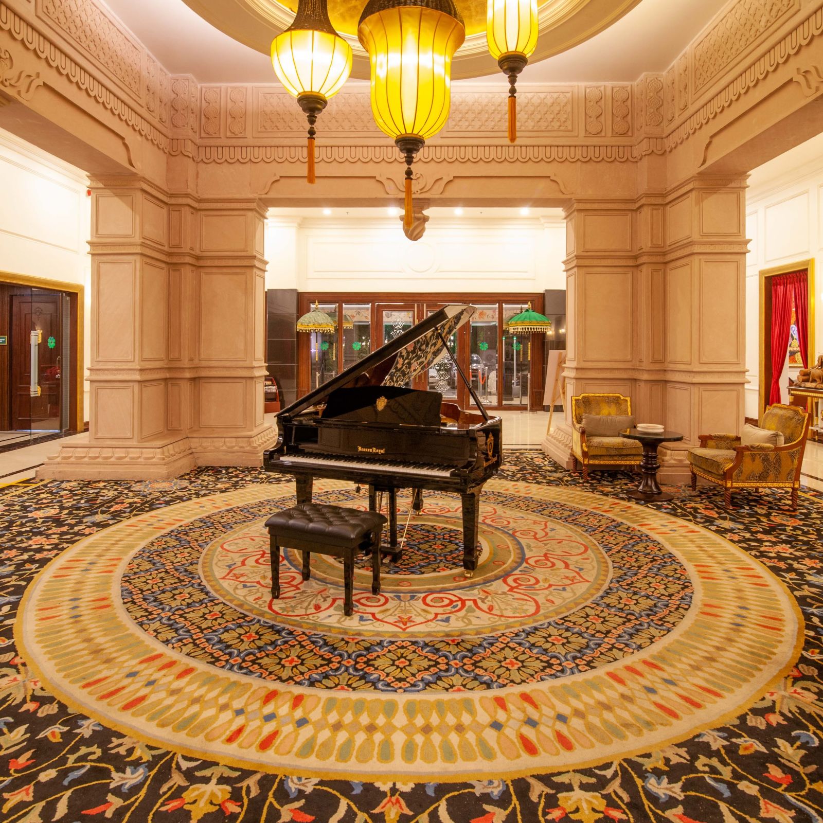 a piano kept in the centre of a room and a chandelier hanging from atop - Mayfair Lake Resort, Raipur 