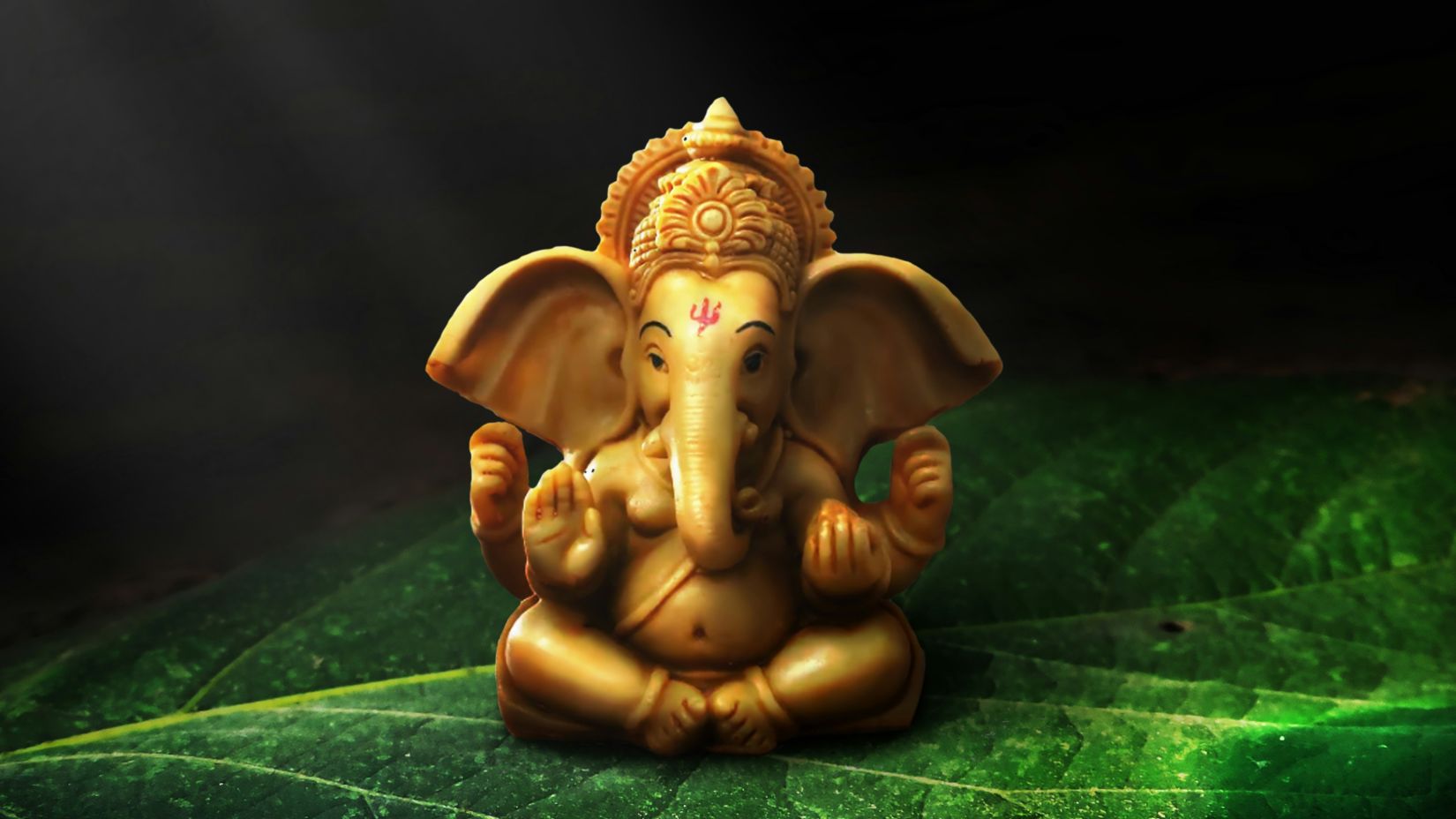 an idol of ganesha kept on a green table with the background blurred