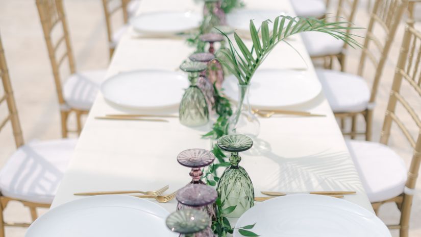 a table with cutlery and plants kept on it during an event