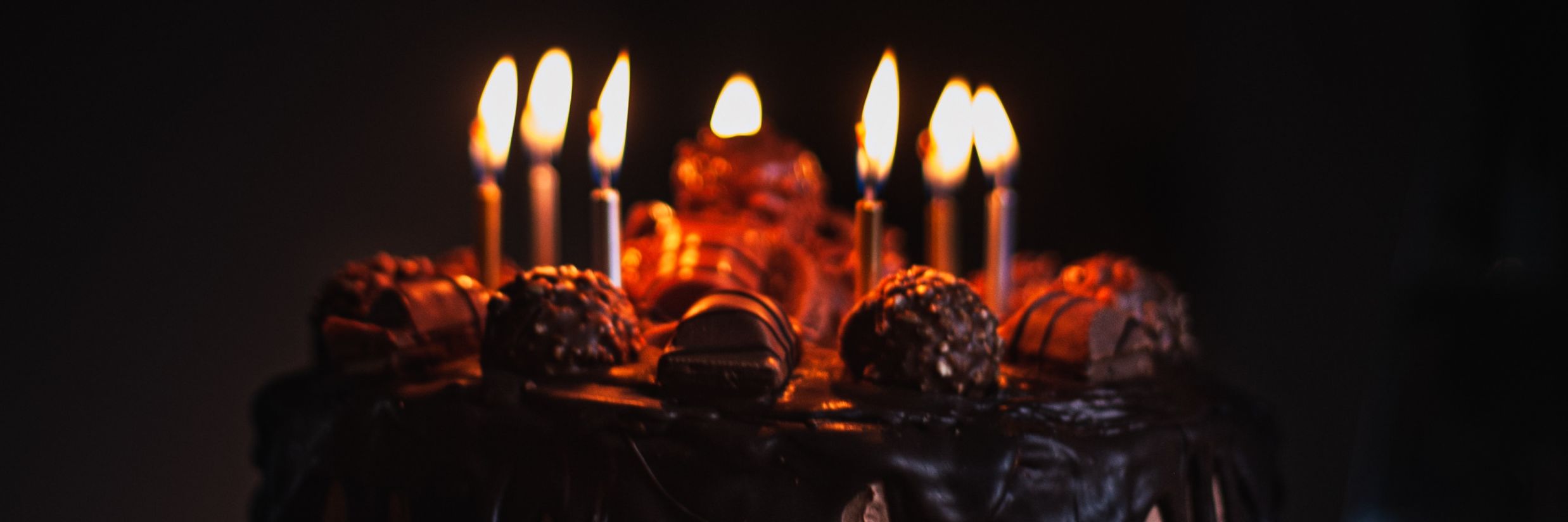 A birthday cake with candles lit and black background