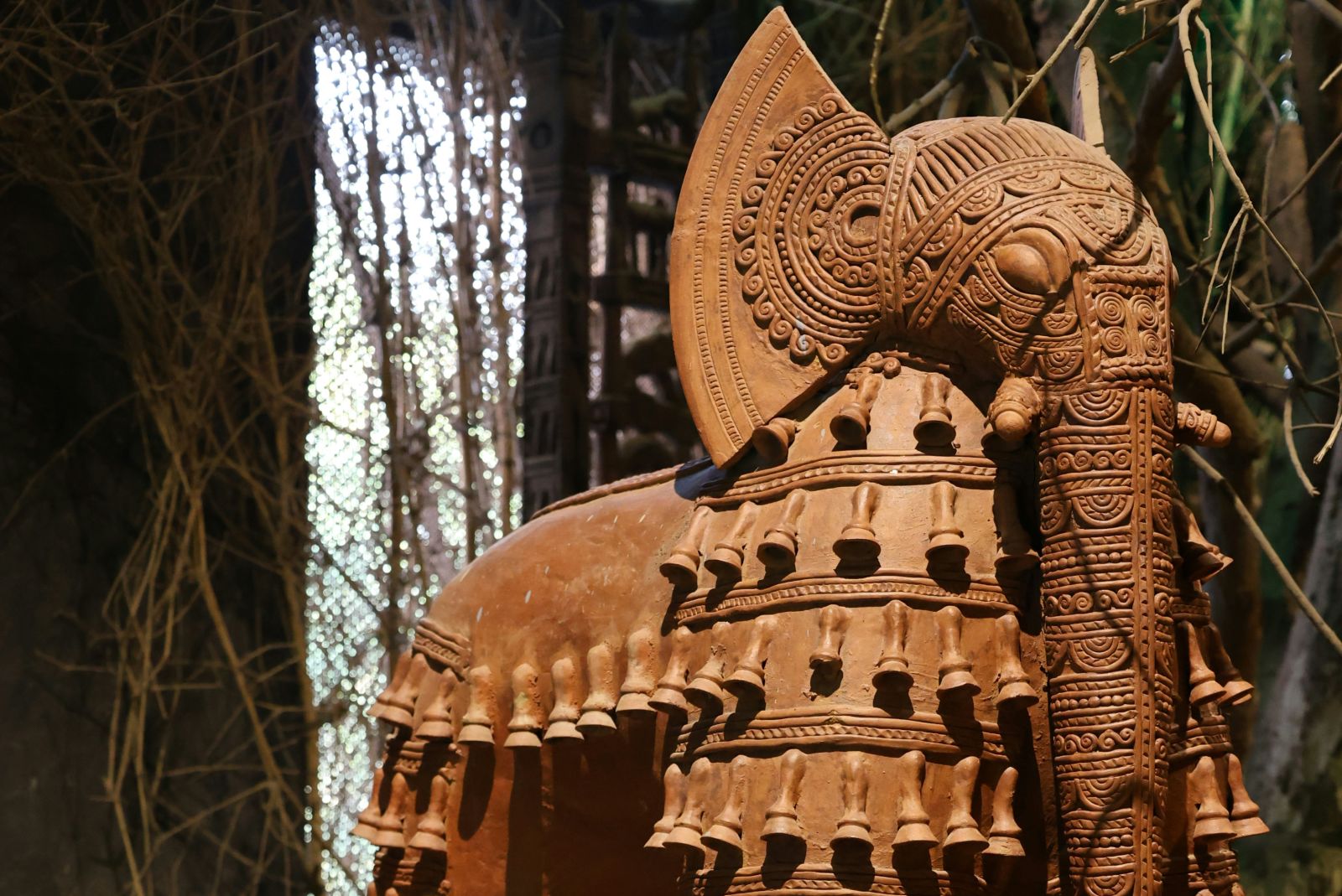 A terracotta sculpture of an elephant adorned with intricate designs and patterns, surrounded by smaller elephant figurines, all showcasing exquisite craftsmanship - Kumarakom