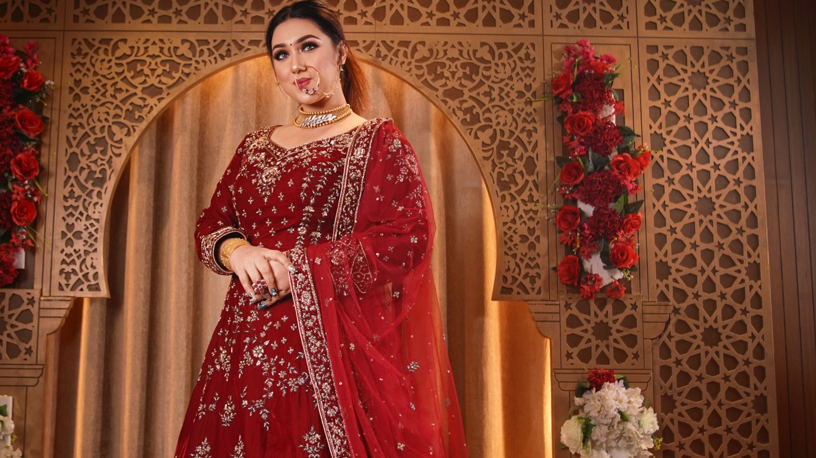 a woman posing wearing a red wedding lehenga