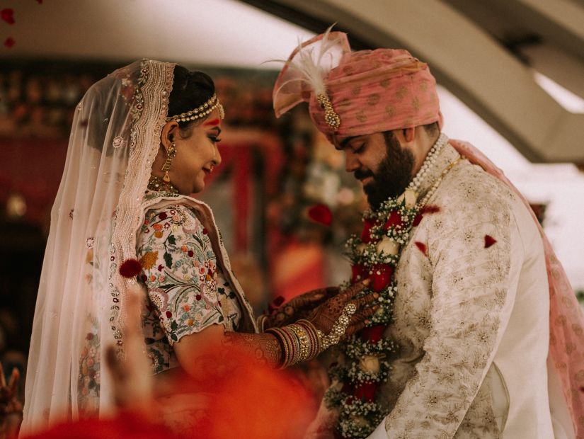 bride and groom standing and performing a ritual while smiling looking at each other