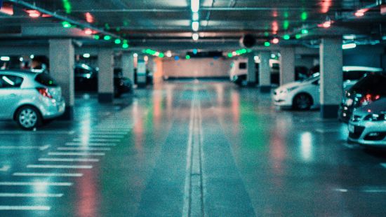 an overview of a parking lot with lights on and cars parked on the side