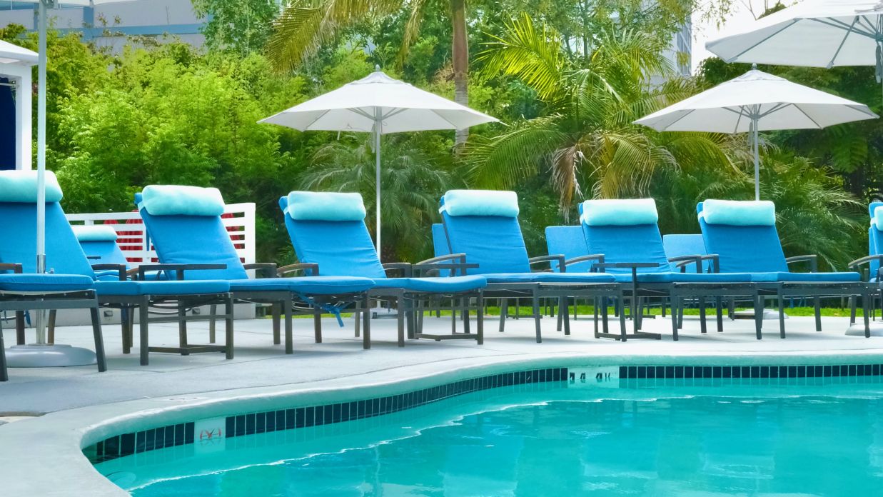 a swimming pool with chairs and umbrellas next to it