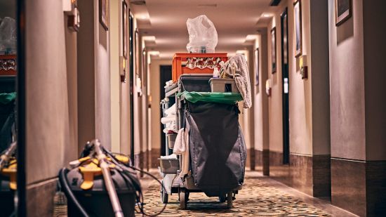 A hotel corridor with a housekeeping cart and cleaning equipment during service hours