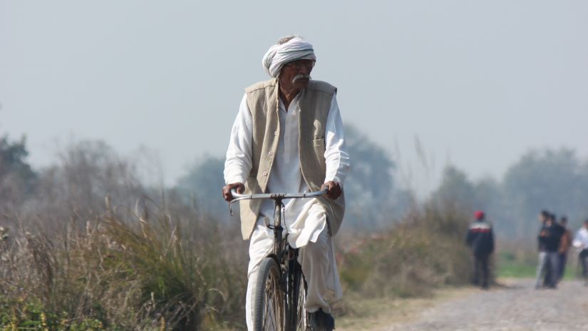 old man cycling in village