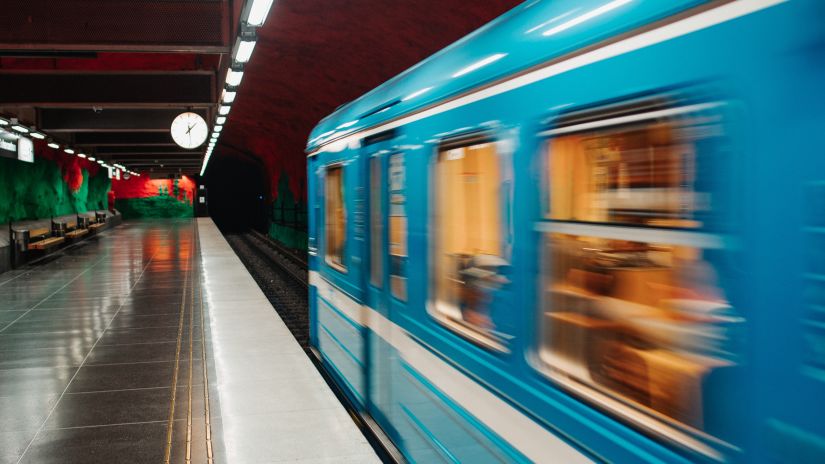 a blue metro passing by in full speed as seen from a train station