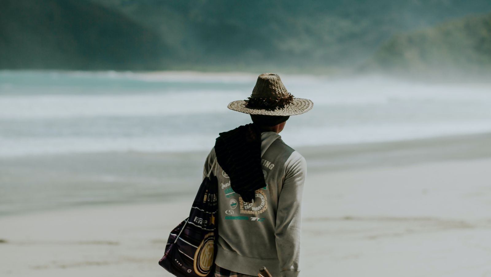 local man walking by the beach with a mountain in the background