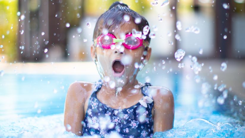 A child wearing swimming goggles looks awe-struck while enjoying the pool - best resort near Delhi with private pool