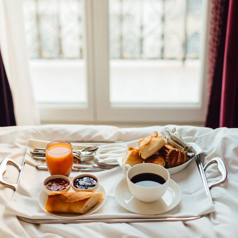 a tray of food on a bed with a cup of coffee