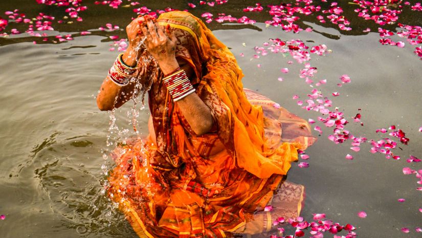 a shot of a women taking dip in The Ganga