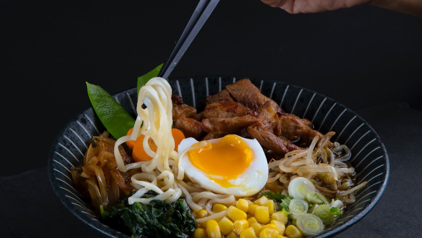 person eating ramen with chopsticks