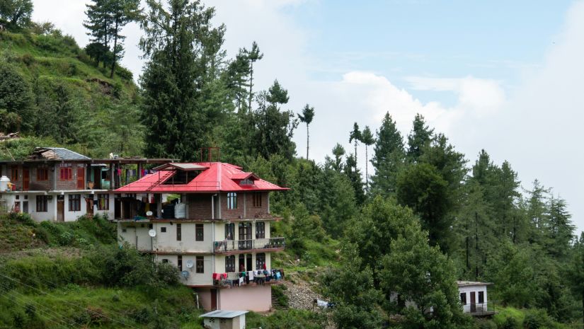 a few building in view on the side of a sloping mountain with trees in the background
