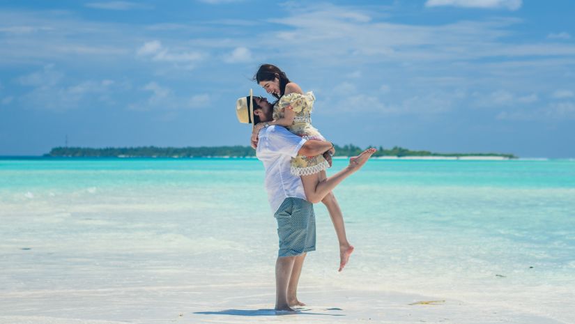 Barefoot At Havelock - image of a couple embracing each other while standing on white sand with the ocean in the background