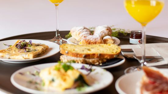 A room service breakfast tray with orange juice and an assortment of breakfast foods on a bed