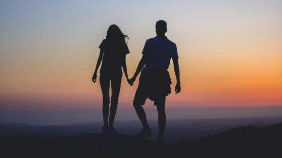 a couple holding hands together during sunset