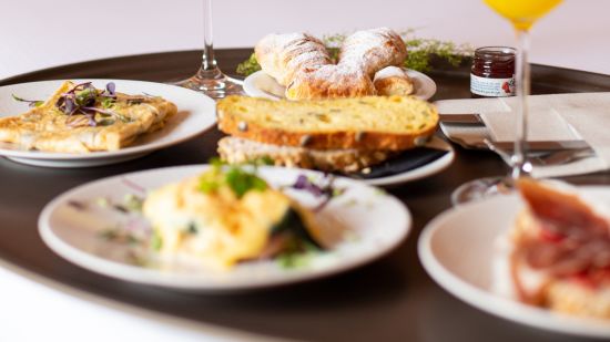 a breakfast tray on bed with many food items and juices