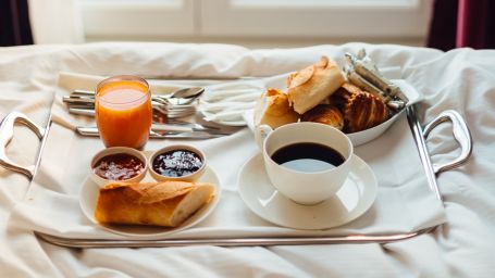 a tray of food on a bed with a cup of coffee