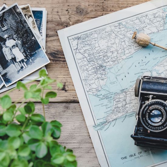 Image of a vintage camera kept on a map which is placed on a table along with photos