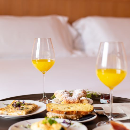 A close shot of food and drinks on a tray placed on the bed