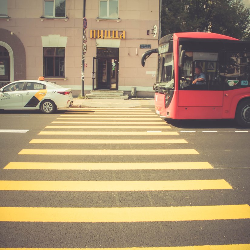 a bus and a cab in between a yellow striped zebra crossing on the road