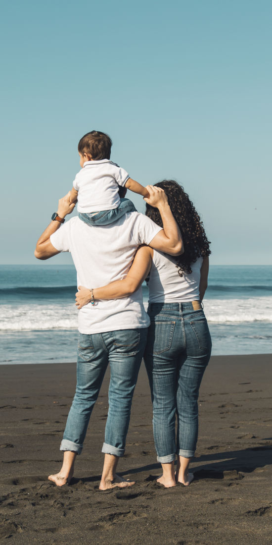 father-holding-baby-neck-hugging-with-wife-beach