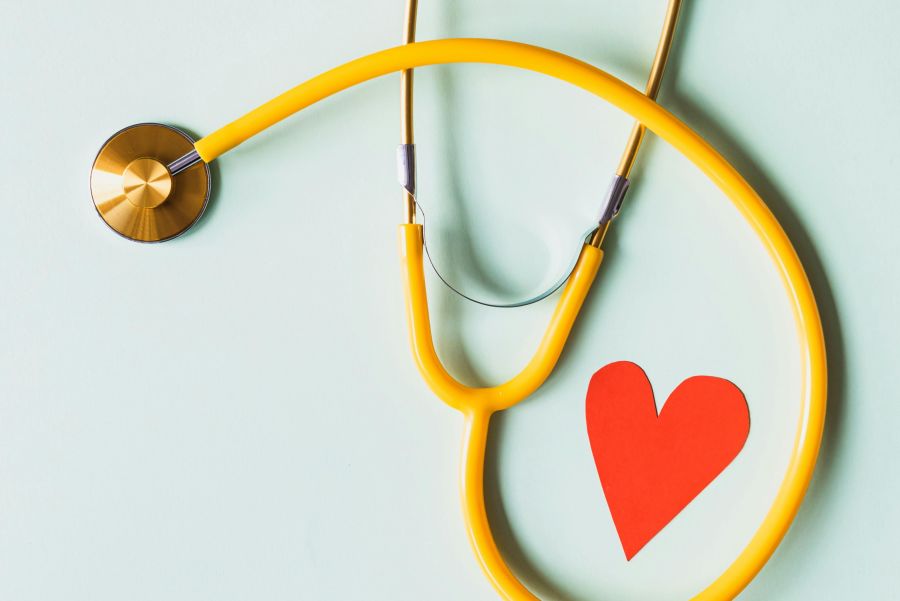 alt-text An yellow stethoscope looping a red paper art of a heart