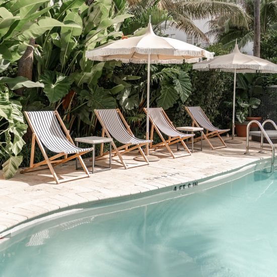 A view of the outdoor swimming pool with sun lounger on the deck