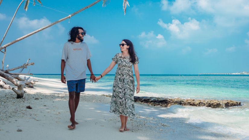 a couple holding hands and walking along a beach