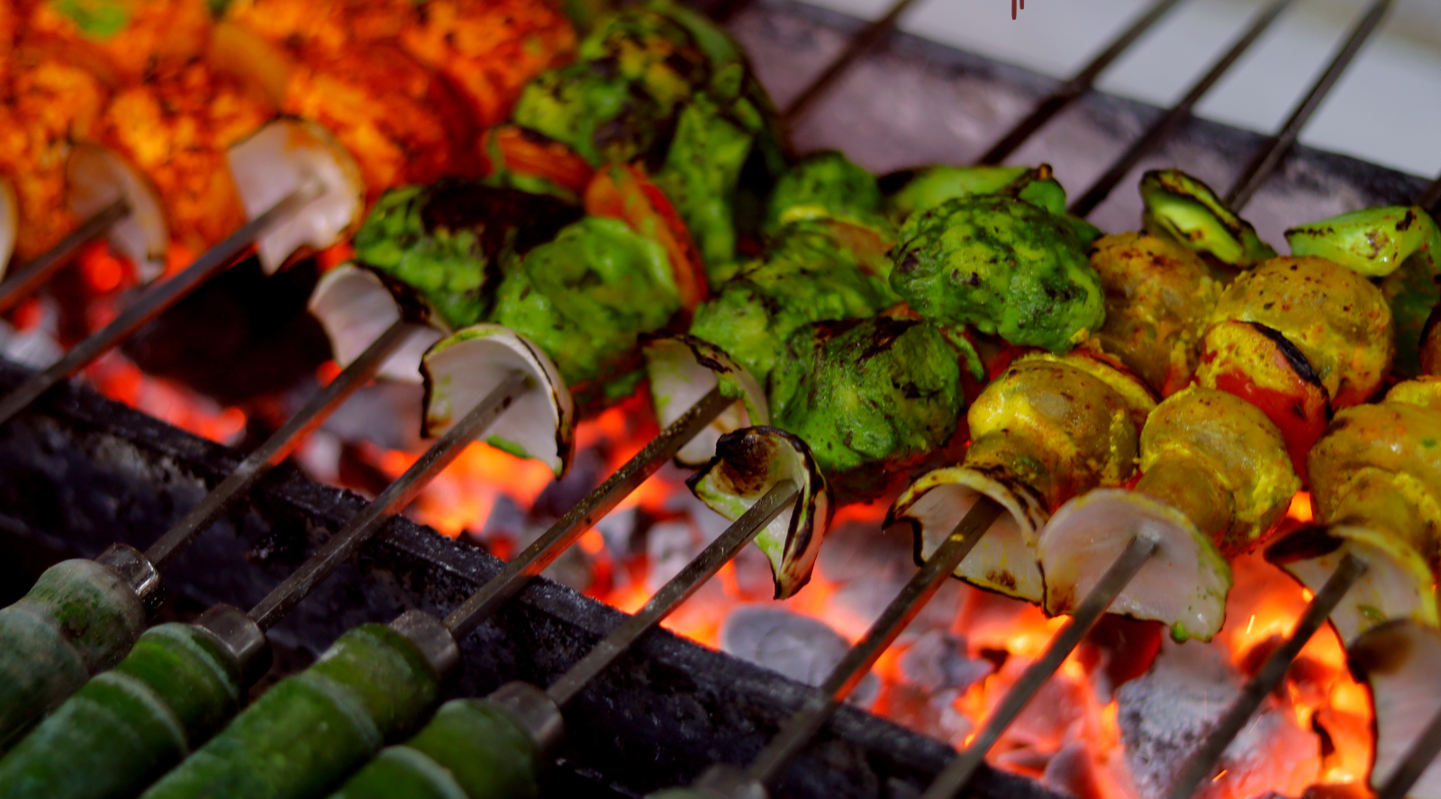 Grilled skewers of paneer, vegetables, and chicken cooking over an open flame at Themis Barbecue House.