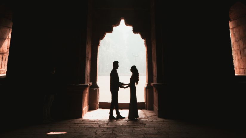 A silhouette man and woman standing under a arched doorway -Fort JadhavGADH 