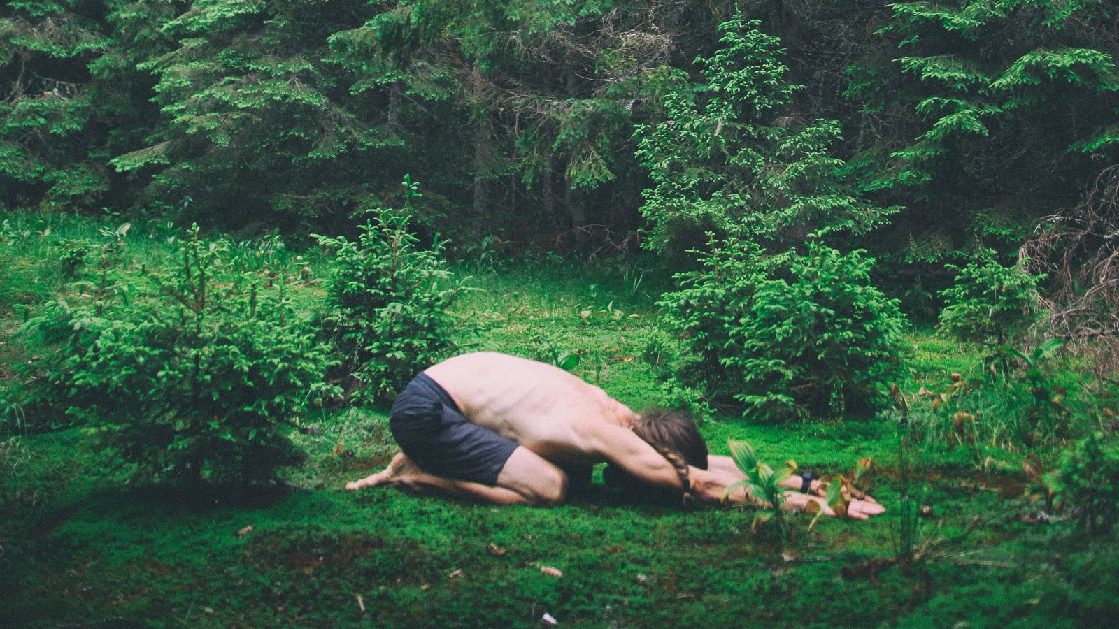 a person performing a yoga asana of child's pose amidst nature