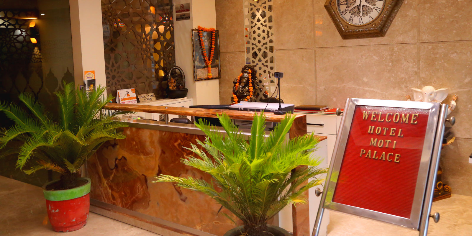 A image of the warmly lit reception of hotel with plants placed around it