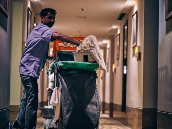 A person carrying a dustbin in the corridor