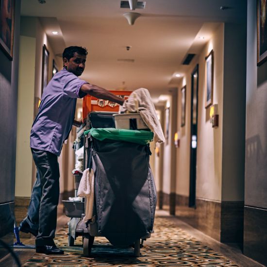 A person carrying a dustbin in the corridor