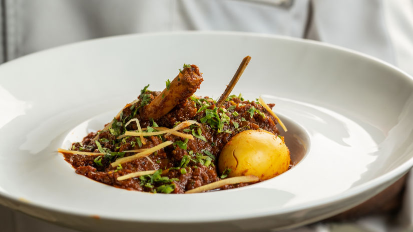 A person holding a meat and egg curry dish