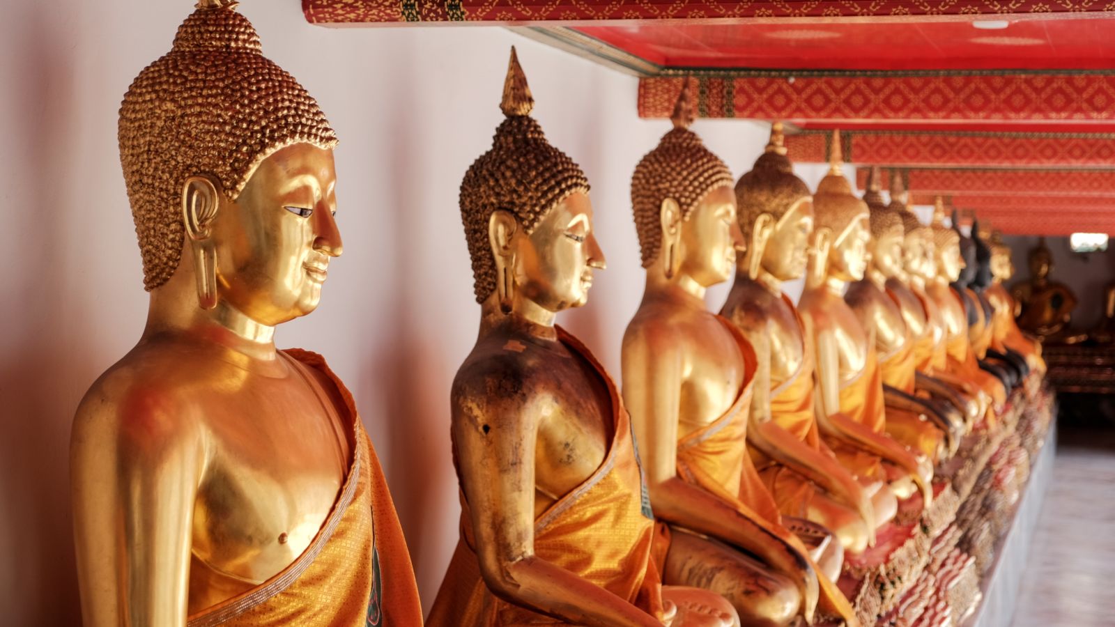 a row of gold plated statue of buddhist monks