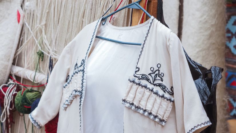 White coloured top for women that features blue coloured embroidery hung in a local market