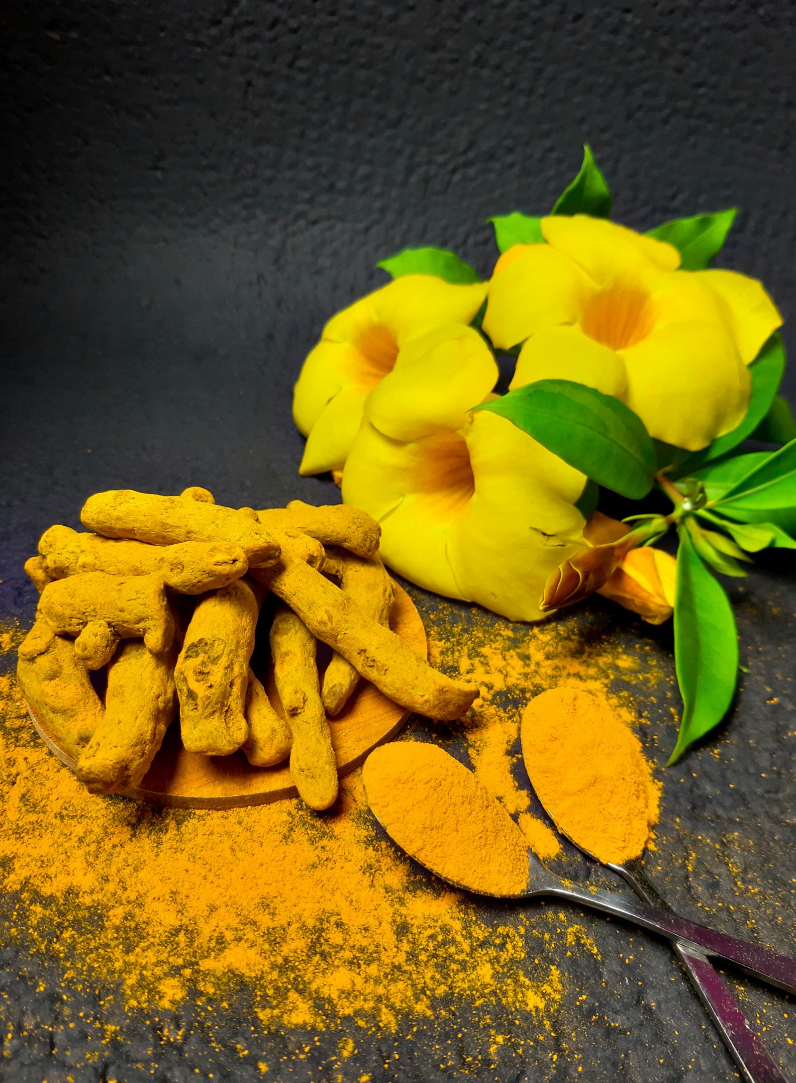 an image showing turmeric as a powder and turmeric pieces with flowers next to it