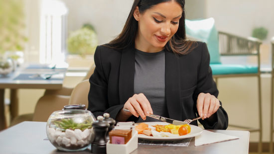 A woman enjoying her food inside La Patio - La Maison Hotel, Doha